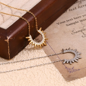 Detail of silver and 18K gold crescent pendant necklaces with inset zircons on vintage wood