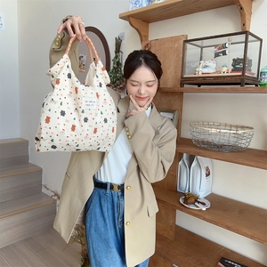 Detail of cartoon rabbit embossed canvas bag with orange checkered handle in life scene