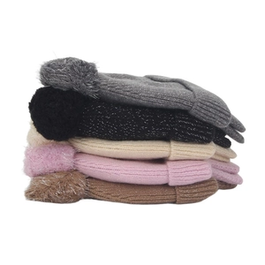 Detailed view of kids' winter knitted hats with fluffy pompoms in five assorted colors
