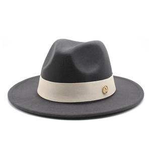 Close-up of a charcoal grey wool fedora hat with beige ribbon and gold logo badge