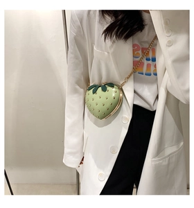 Detail of light green strawberry-shaped bag with gold studs and metal chain strap