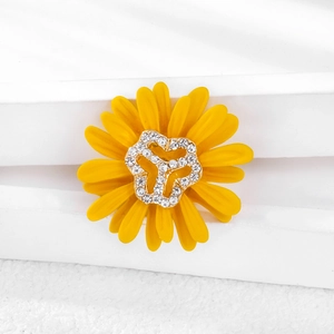 Macro detail of yellow daisy brooch featuring enamel petals and a sparkling rhinestone center
