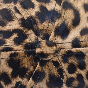 Dettaglio macro del cappello leopardato in pelle PU con cuciture e bottone superiore
