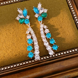 Close-up of vintage flower earrings with blue and green crystals in a retro frame