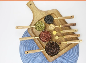 Flat lay of 8-piece stainless steel measuring cups with acacia wood handles and legumes