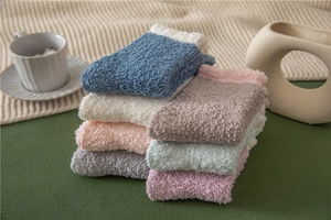 Close-up of soft coral fleece slipper socks in various pastel colors on a cozy blanket