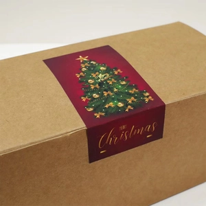 Detail of red Merry Christmas sticker with gold text on a kraft paper gift box