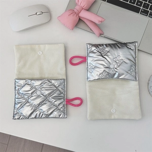 Close-up of silver quilted heart pouch with butterfly embossing and snap closure detail