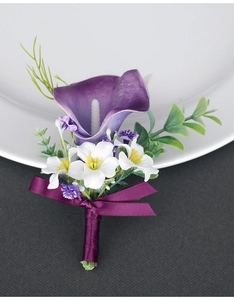 Detail of handmade purple calla lily boutonniere with satin ribbon on white porcelain