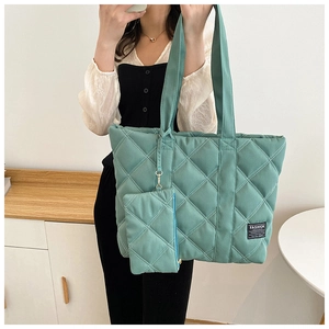Detail of green quilted puffer tote bag with matching mini coin purse on handle