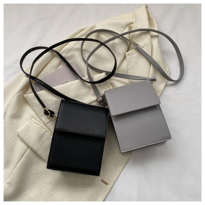 Sacs à bandoulière minimalistes en cuir PU noir et gris posés sur un blazer chic