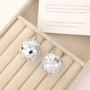 Fashionable silver disco ball mirror earrings displayed on a minimalist jewelry tray