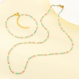 Détail du set collier et bracelet dorés ornés de perles en résine roses, bleues et violettes