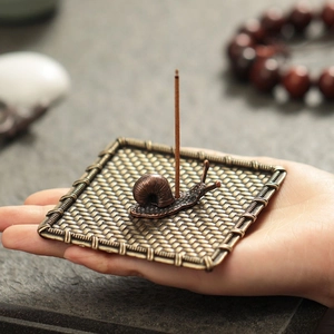 Mini porta incenso a chiocciola in bronzo con base intrecciata tenuto in mano per misura