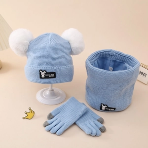 Detail of light blue winter knit hat set with soft fleece lining and white faux fur pom poms