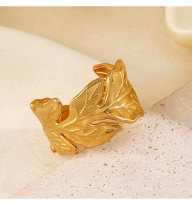 Detailed macro view of a gold leaf open ring featuring intricate texture on stone backdrop