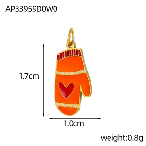 Macro view of orange and red enamel glove charm with white polka dots and heart detail