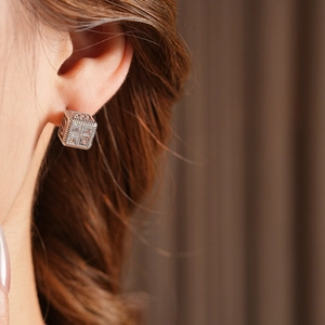 Gros plan d'une boucle d'oreille carrée en zircon avec lettre M sur le lobe