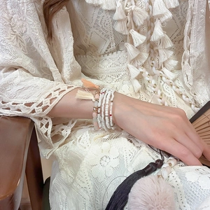 Detail of bohemian multilayer beaded bracelet set with pink tassels and white crystals