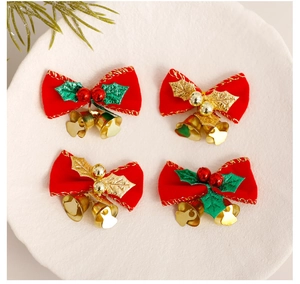 Flat lay of red Christmas bow ornaments with gold bells and green leaves on beige background