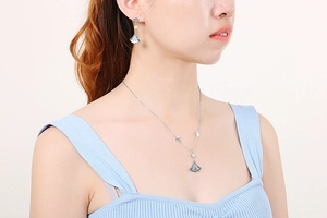 Detail of model wearing silver fan-shaped necklace and rhinestone earrings set