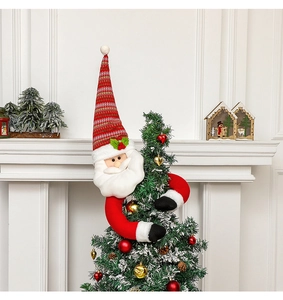 Detail of plush Santa Claus tree topper hugging the top of a decorated Christmas tree