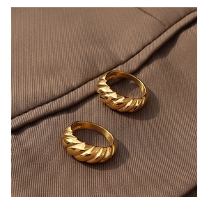 Detailed close-up of golden croissant-style twisted rings on premium beige fabric