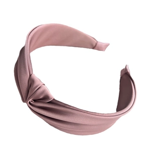 Elegant pink fabric headband with a stylish twist knot design on a clean white background