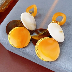 Detailed close-up of resin round pattern earrings with tassels in brown and orange tones
