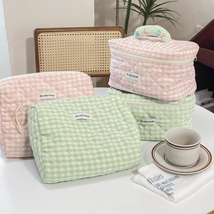 Detailed view of pink and green checkered quilted cotton makeup bags in a lifestyle setting
