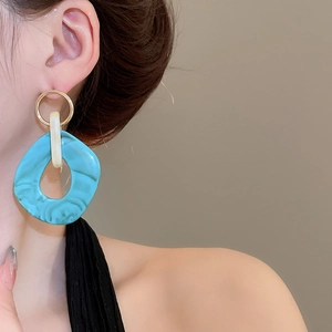 Close-up of irregular turquoise marble resin earrings on model for a trendy fashion look