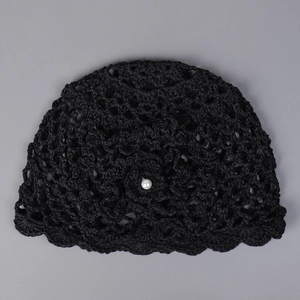 Détail d'un chapeau au crochet noir avec motif ajouré et ornement en perle blanche