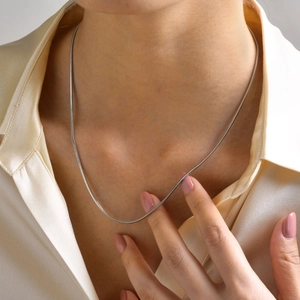Close-up of minimalist silver stainless steel snake chain worn by a model in a shirt
