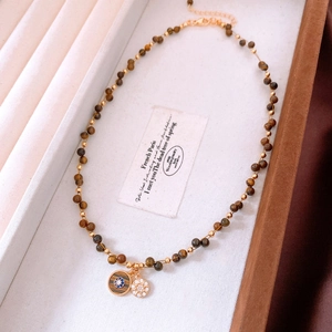 Détail du collier de perles en œil de tigre plaqué or 18k avec double pendentif chic
