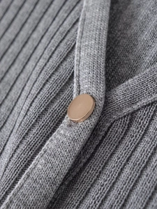 Close-up of ribbed knit texture in grey fabric with a decorative gold metal button