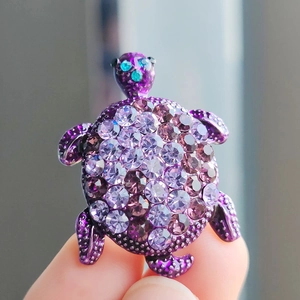 Detailed close-up of a purple turtle brooch featuring crystal rhinestones and blue gem eyes