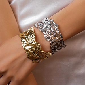Close-up of gold and silver wide cuff bracelets with irregular crumpled metal texture