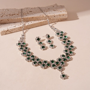 Detailed view of silver necklace and earring set with green gems and zircons