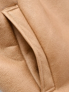 Detailed close-up of textured leather surface and precise stitching on vest pocket