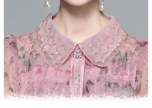 Détail d'un col claudine avec perles roses et cristaux sur une robe en tulle