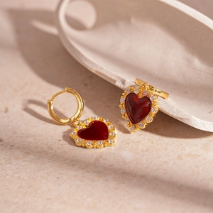 Vintage red heart hoop earrings with gold plating and cubic zirconia on stone background