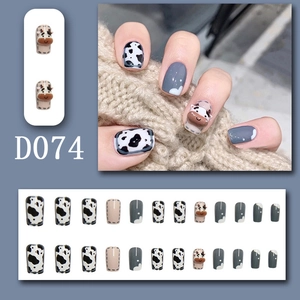 Detail of short square press-on nails with 3D cow patterns and grey cow print designs