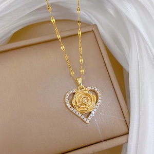 Macro view of gold heart pendant with internal rose and cubic zirconia inlay
