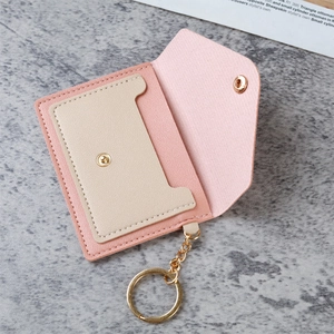 Pink and beige PU leather card holder with gold keychain on marble background