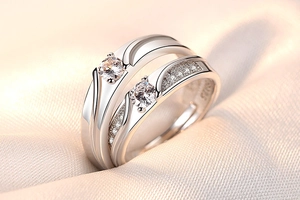 Close-up of couple silver rings with sparkling zircon stones on pearl fabric