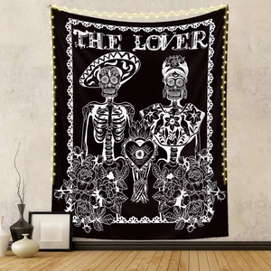 Detail of The Lover tarot tapestry with skulls and roses hanging on a wall with lights