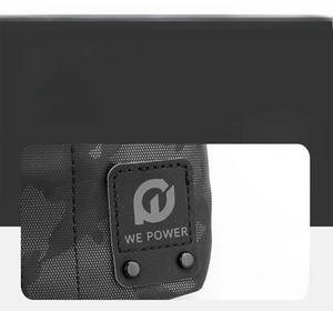 Dettaglio della placca logo in pelle nera con rivetti metallici su borsa camouflage