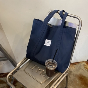 Minimalist navy blue canvas tote bag on industrial chair with coffee for daily commute