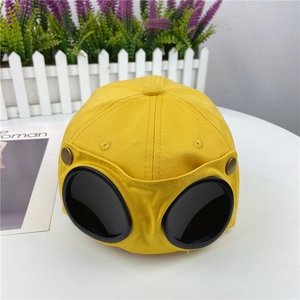 Detail of pilot-style goggles on a bright yellow cotton baseball cap with bronze buttons