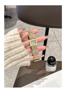 Gros plan d'une montre carrée dorée avec cadran vert sur un fond de style vie élégante